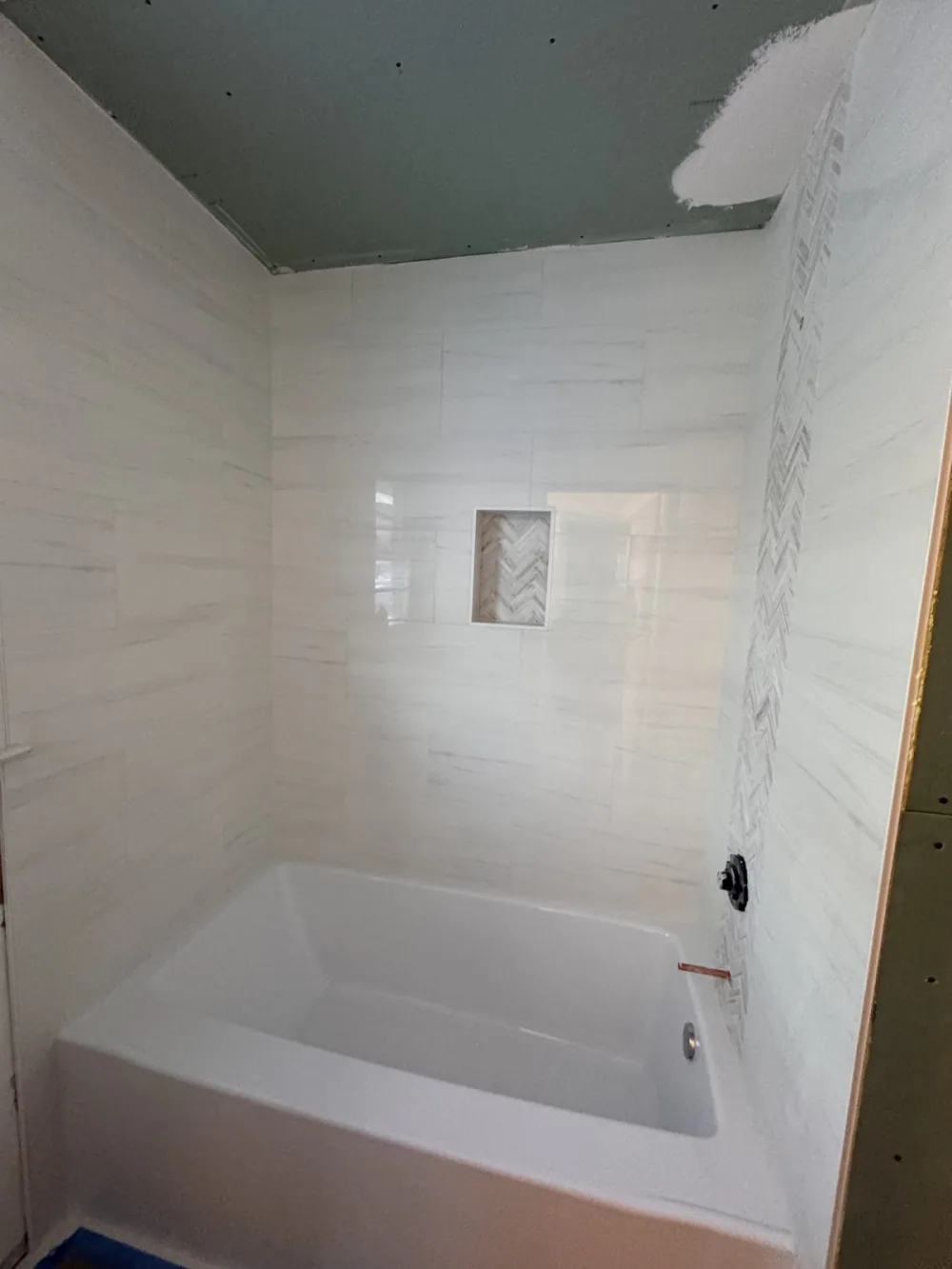 New bathtub with a large-format white porcelain surround and niche during a full bathroom remodel in Philadelphia