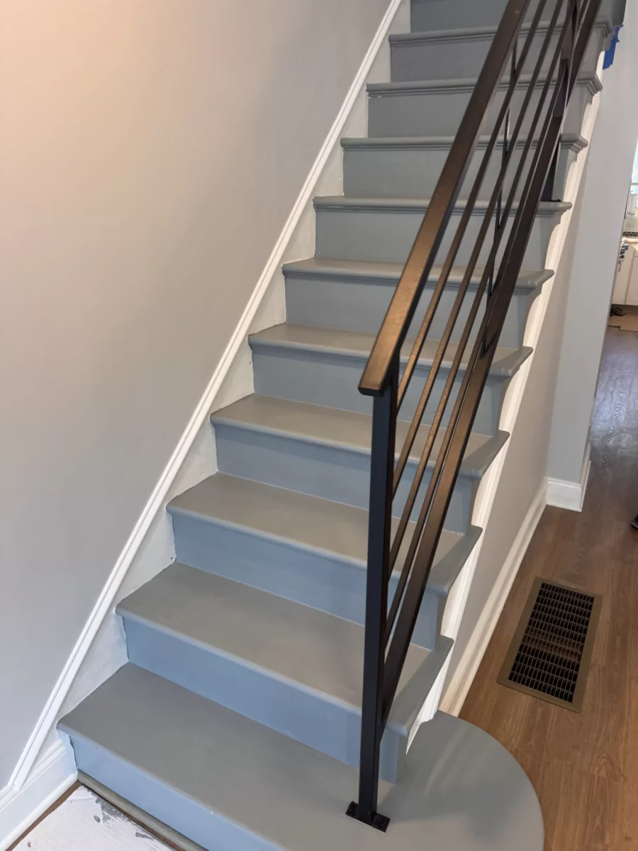 Rowhome staircase with gray treads, white risers and a black metal railing in Philadelphia