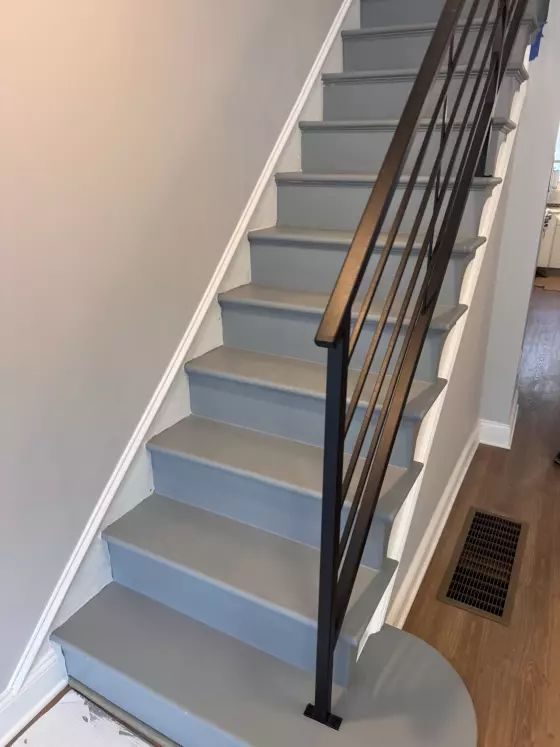 Rowhome staircase with gray treads, white risers and a black metal railing in Philadelphia