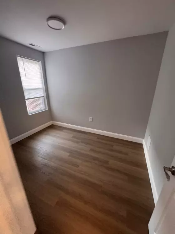 Painted bedroom with wood-look plank flooring and white baseboards
