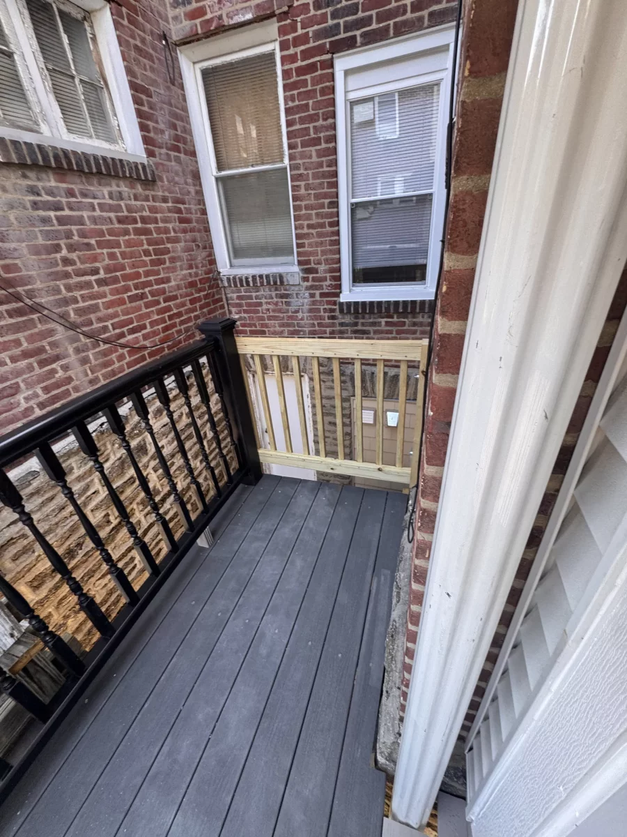 Composite rear deck with black balusters against the brick back wall of a rowhome