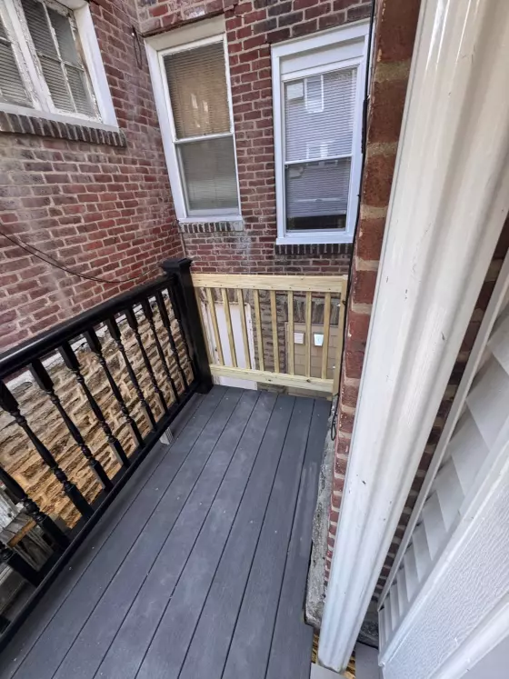 Composite rear deck with black balusters against the brick back wall of a rowhome