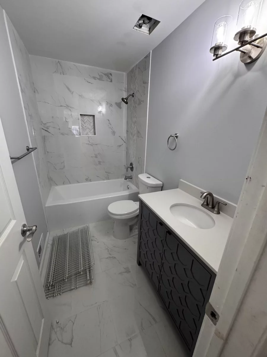 Bathroom with marble-look tile, a soaking tub, a dark vanity and a towel warmer in Princeton, NJ