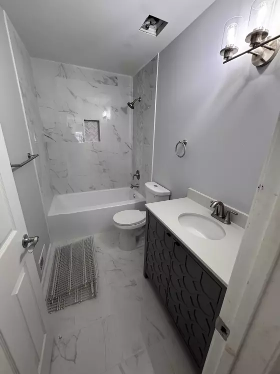 Bathroom with marble-look tile, a soaking tub, a dark vanity and a towel warmer in Princeton, NJ
