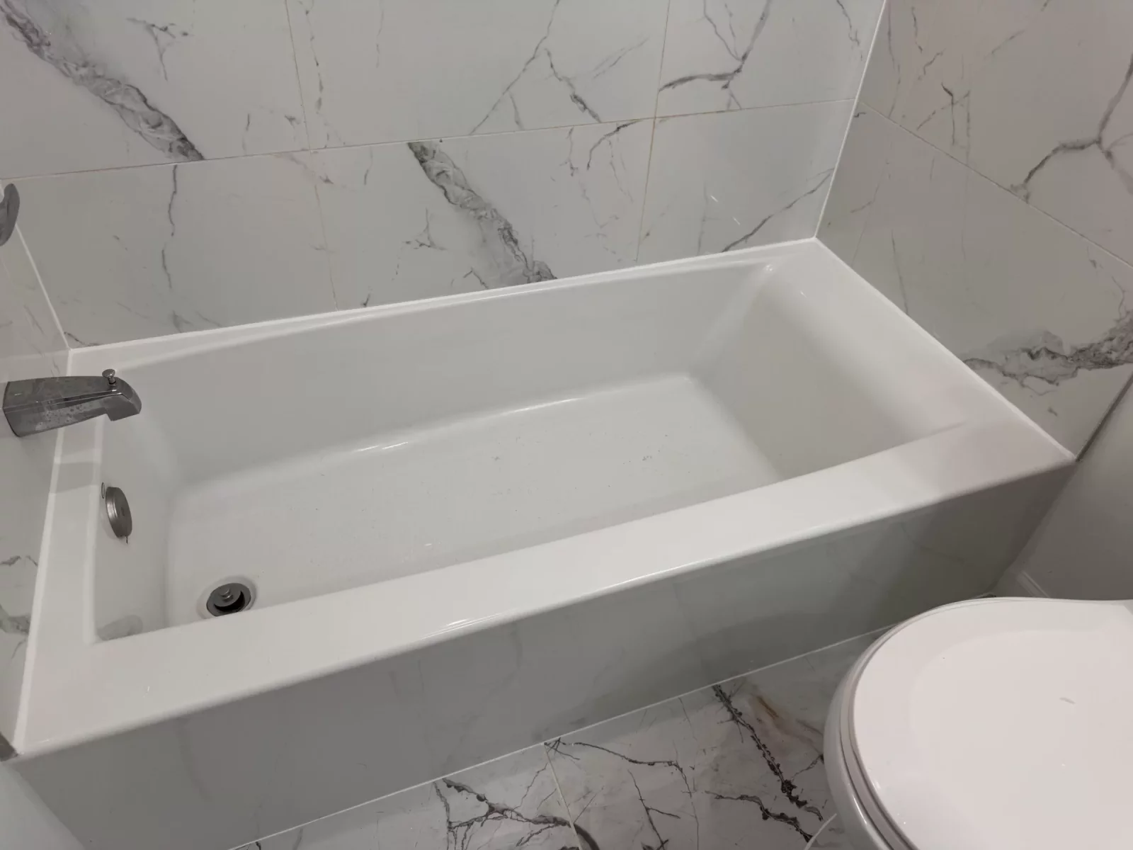 Soaking tub framed by marble-look porcelain walls and floor