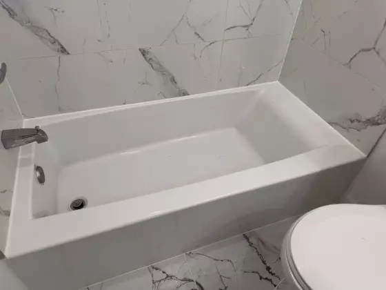 Soaking tub framed by marble-look porcelain walls and floor
