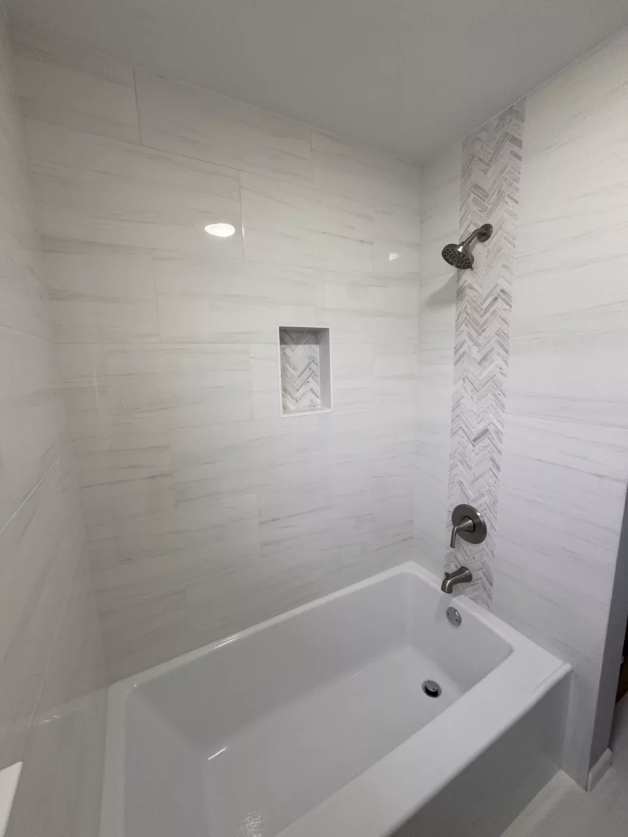 Recessed shower niche with herringbone tile above a soaking tub
