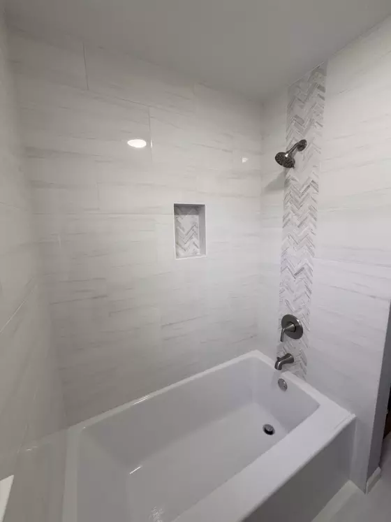 Recessed shower niche with herringbone tile above a soaking tub