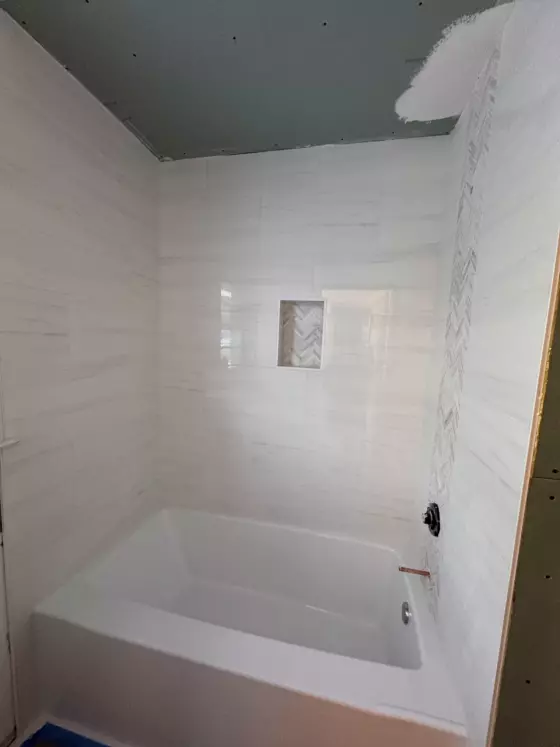 White porcelain tub surround with a herringbone tile niche
