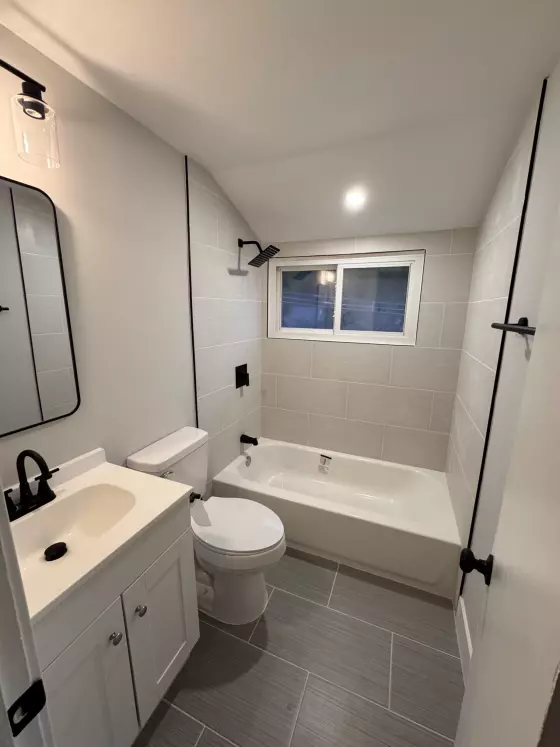 Bathroom with gray plank tile floor, white vanity and matte black faucet