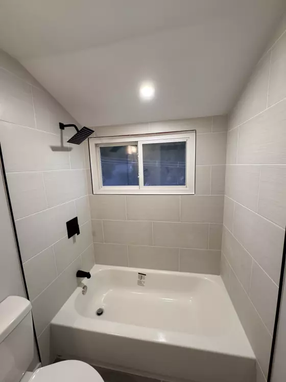 Tub with a light tile surround, black rain showerhead and window