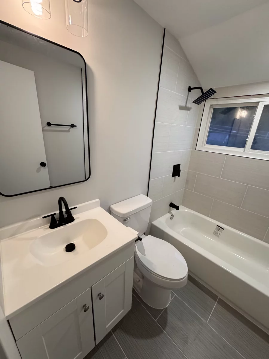 White vanity with matte black faucet and a rounded black-framed mirror