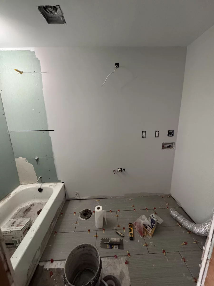 Floor tile leveling clips and plumbing rough-in during a bathroom remodel