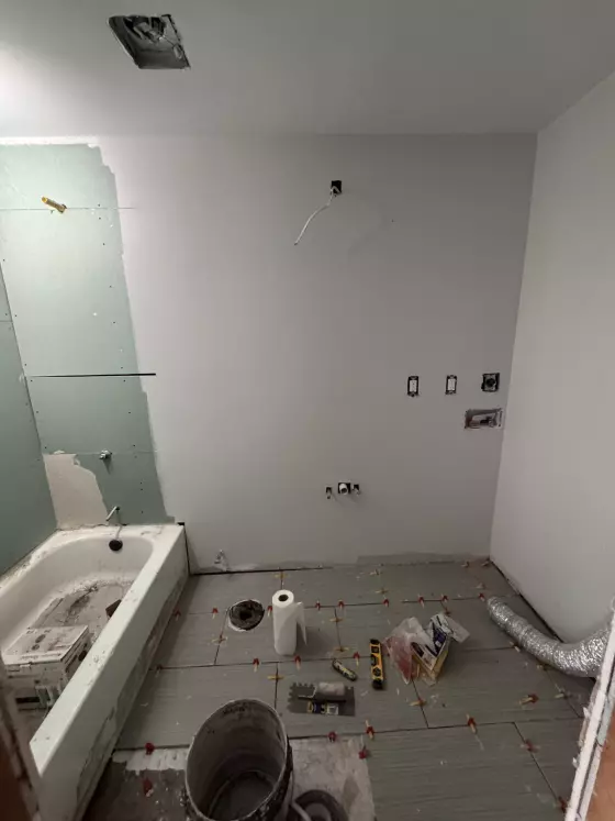 Floor tile leveling clips and plumbing rough-in during a bathroom remodel