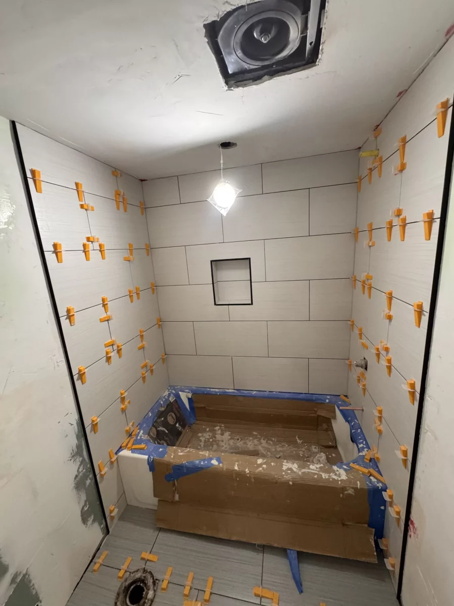 Tile leveling system on fresh wall and floor tile during a bathroom remodel