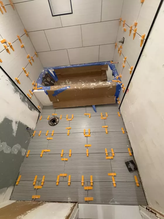 Gray plank floor tile being set around a protected tub