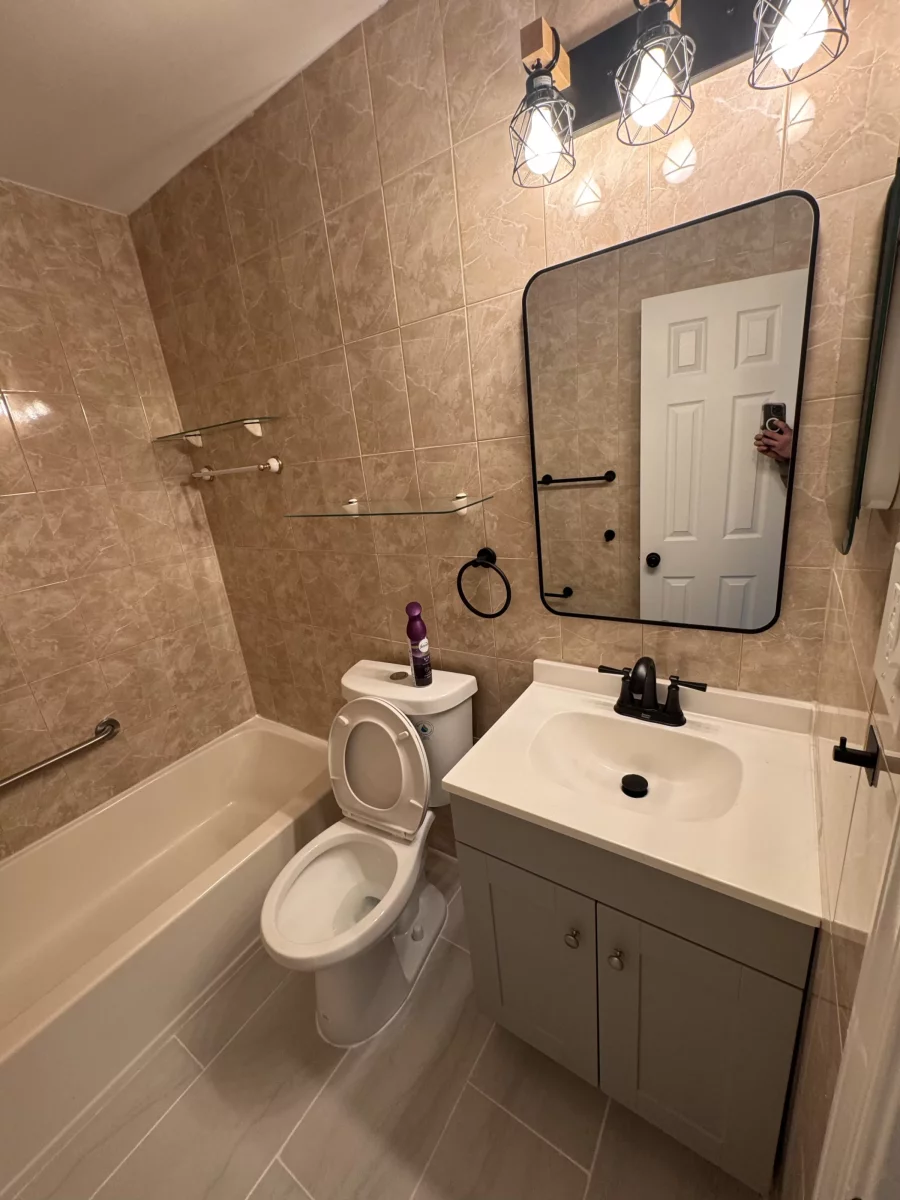 Bathroom with a gray vanity, black-framed mirror, black light fixture and light gray tile floor