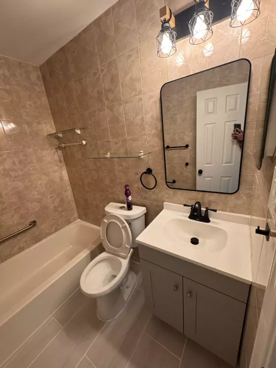 Bathroom with a gray vanity, black-framed mirror, black light fixture and light gray tile floor