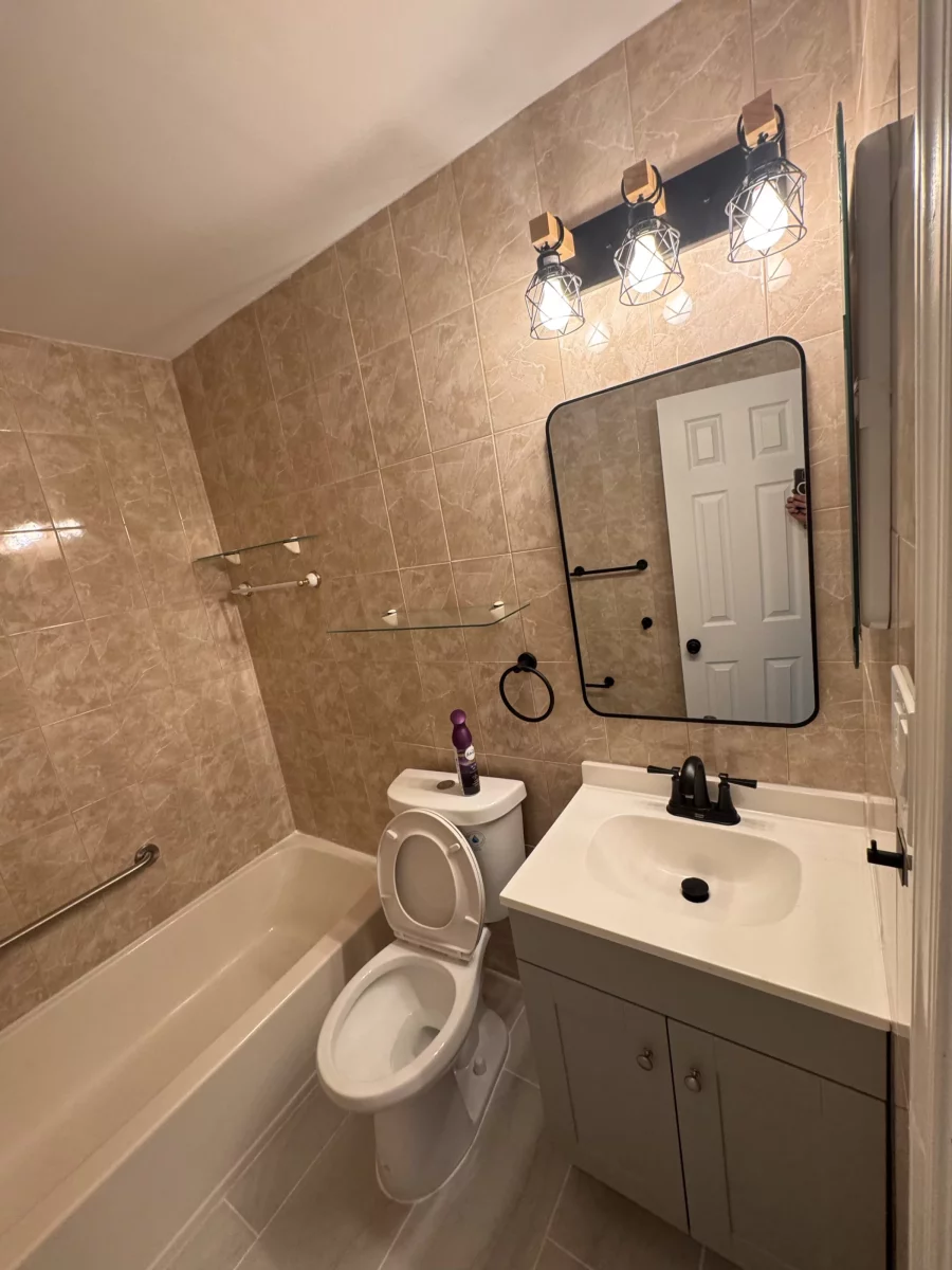 Gray shaker vanity with white top and matte black faucet under a black-framed mirror
