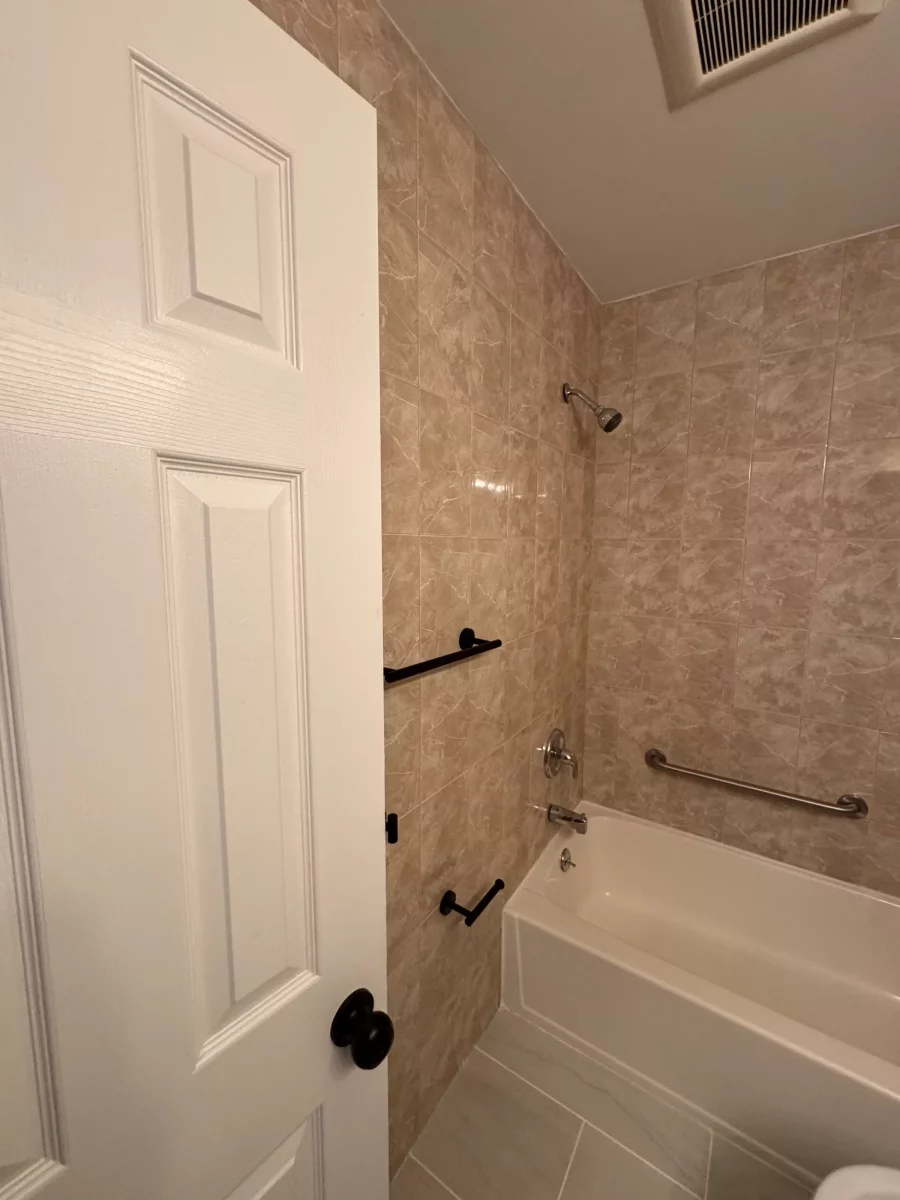 Tub with grab bars and a matte black towel bar