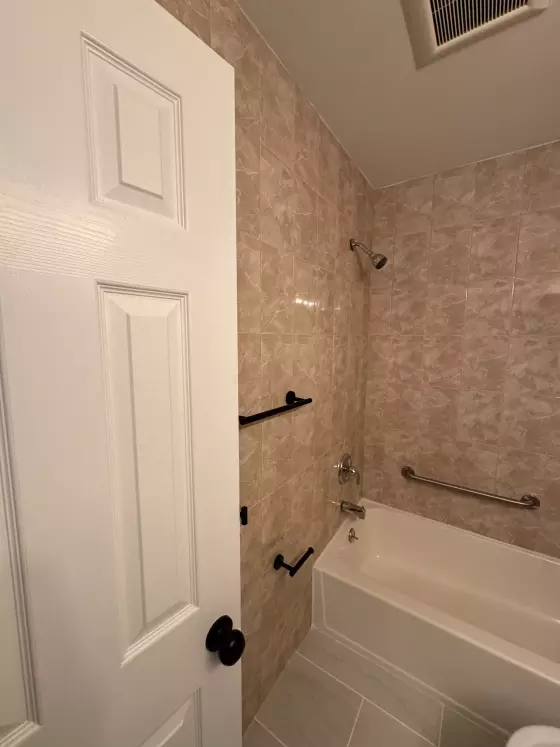 Tub with grab bars and a matte black towel bar