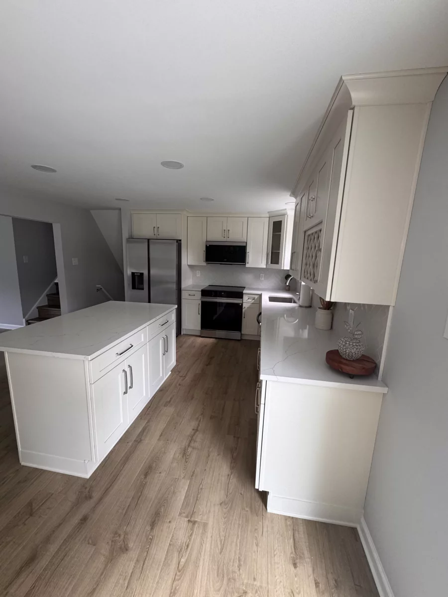 Kitchen island with white quartz top and cream shaker cabinets with crown molding
