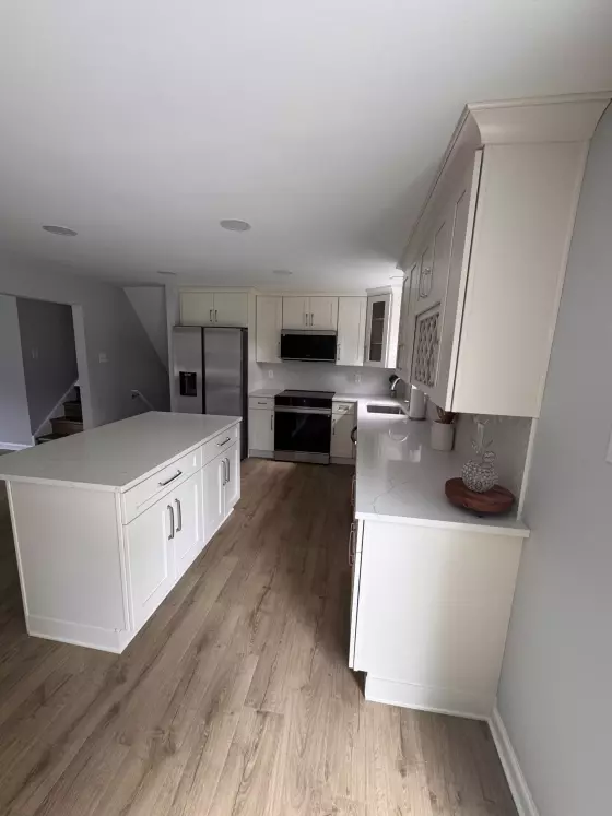 Kitchen island with white quartz top and cream shaker cabinets with crown molding