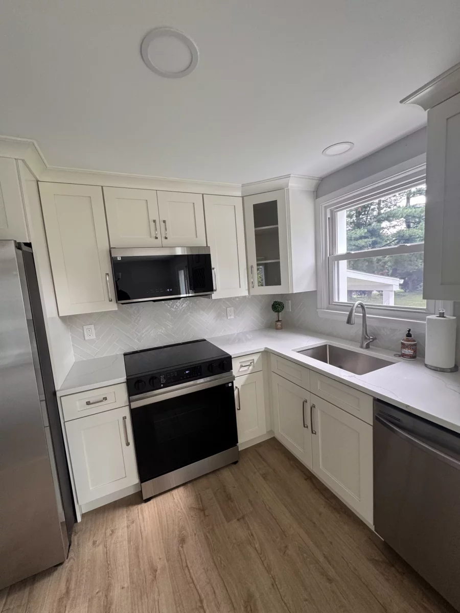 Cream shaker cabinets, glass-front cabinet, stainless range and microwave around a corner sink