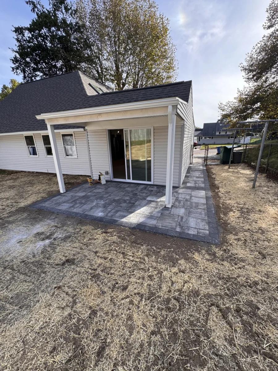 Rebuilt rear of the house with a covered porch, sliding door and gray paver patio in Levittown