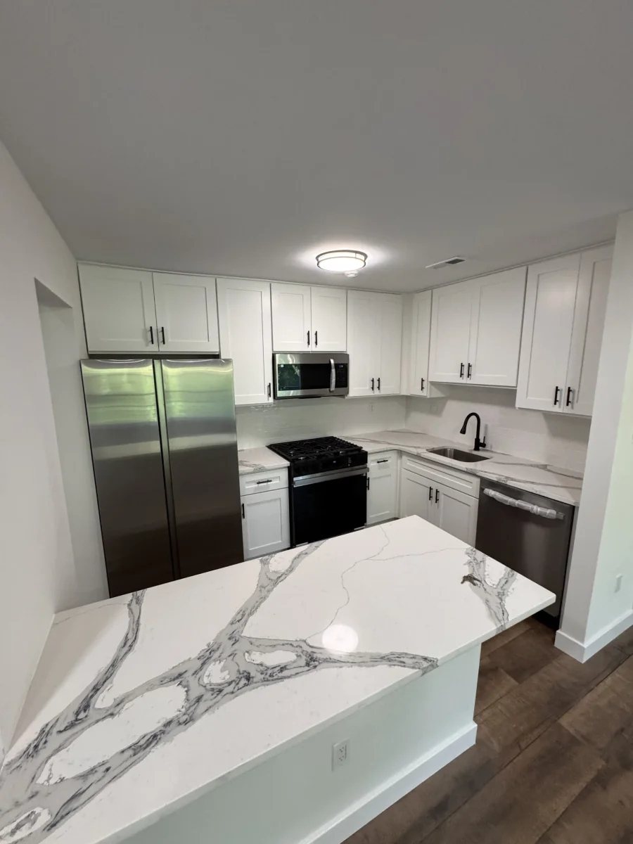 Kitchen with a marble-look quartz island and dark wood-look flooring in a renovated Newtown home