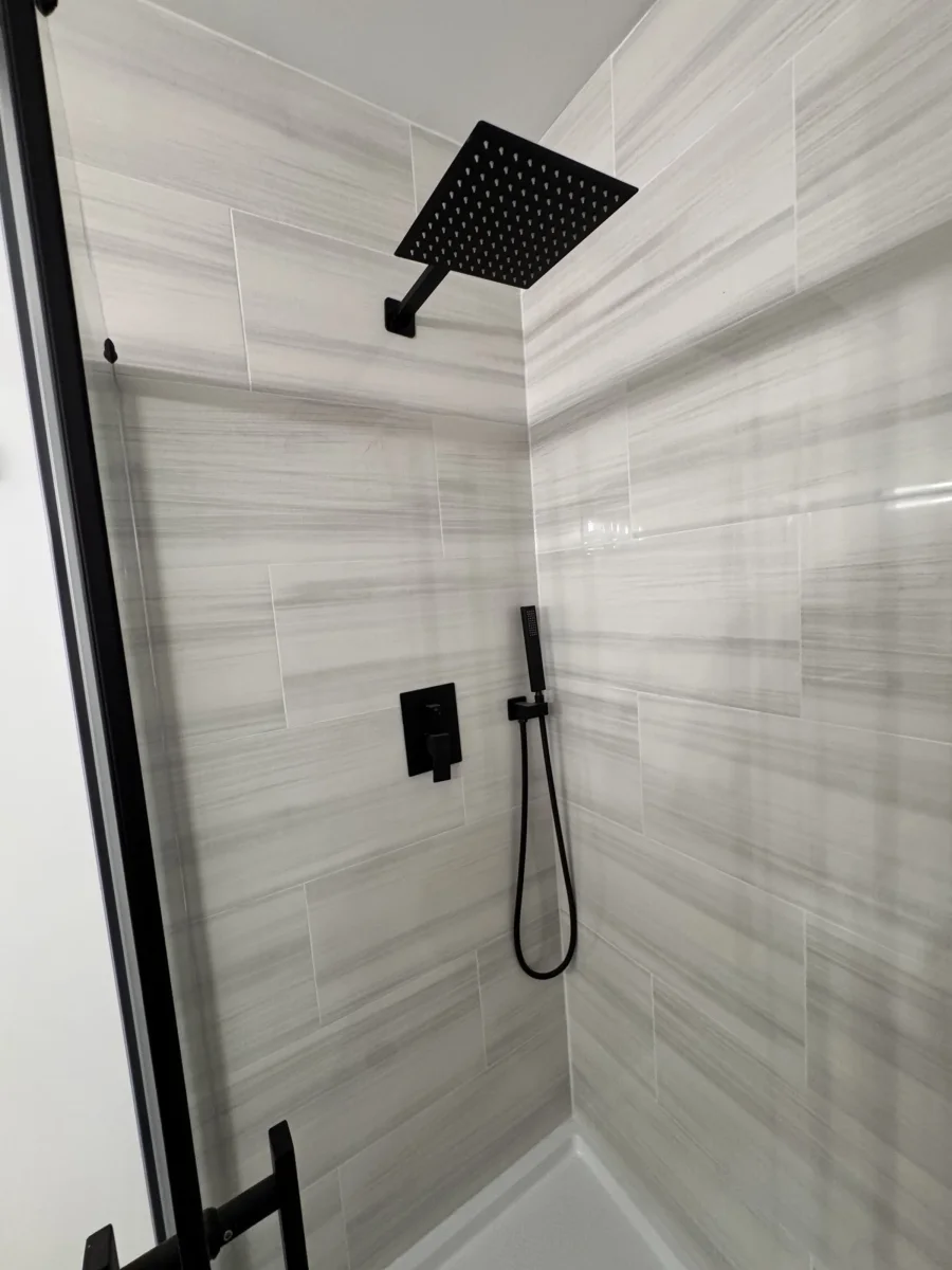 Walk-in shower with gray stone-look wall tile, matte black rain head and hand shower in Newtown