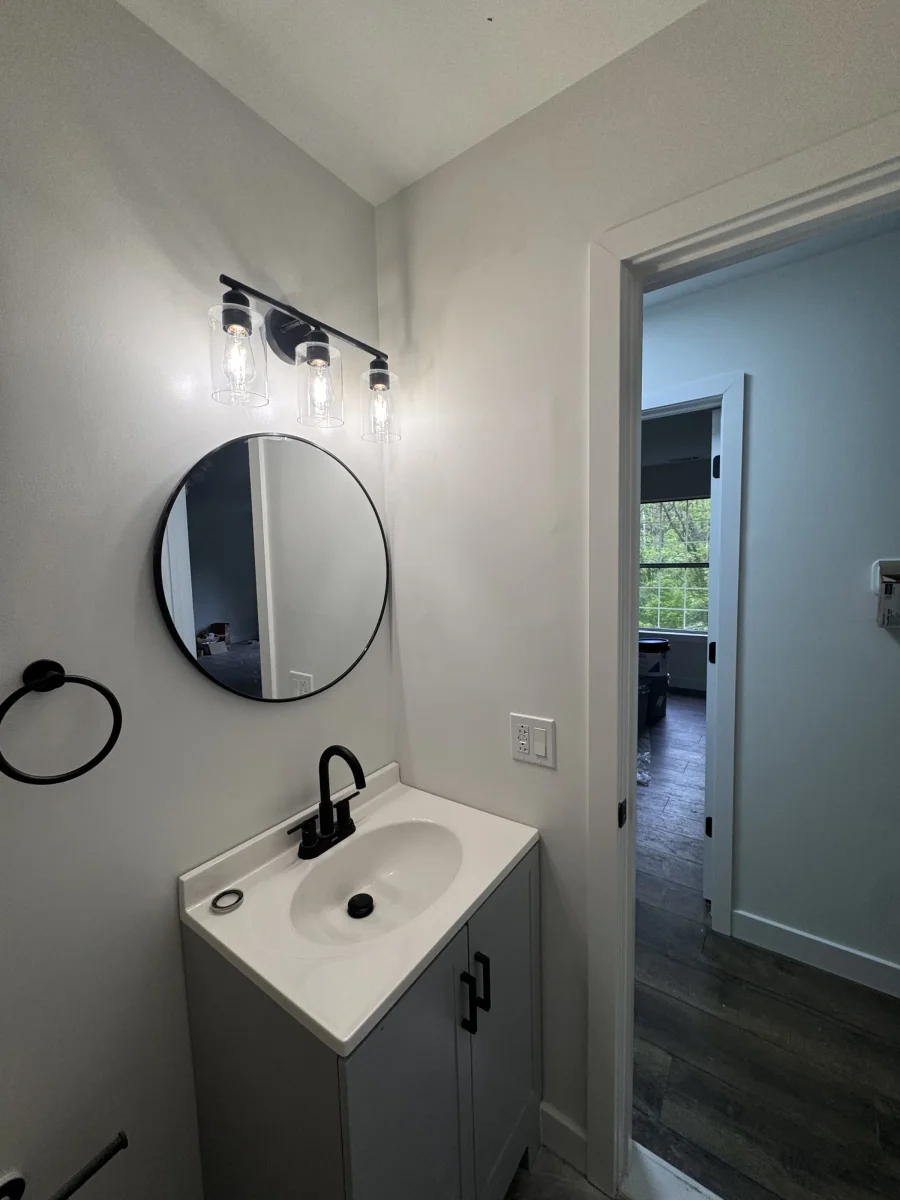 Gray vanity with a round black mirror and black vanity light