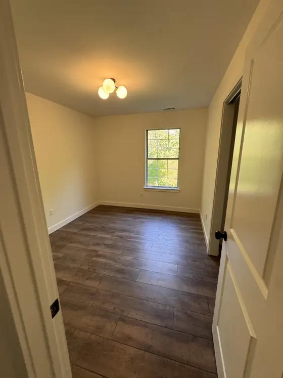 Bedroom with warm paint and dark wood-look flooring
